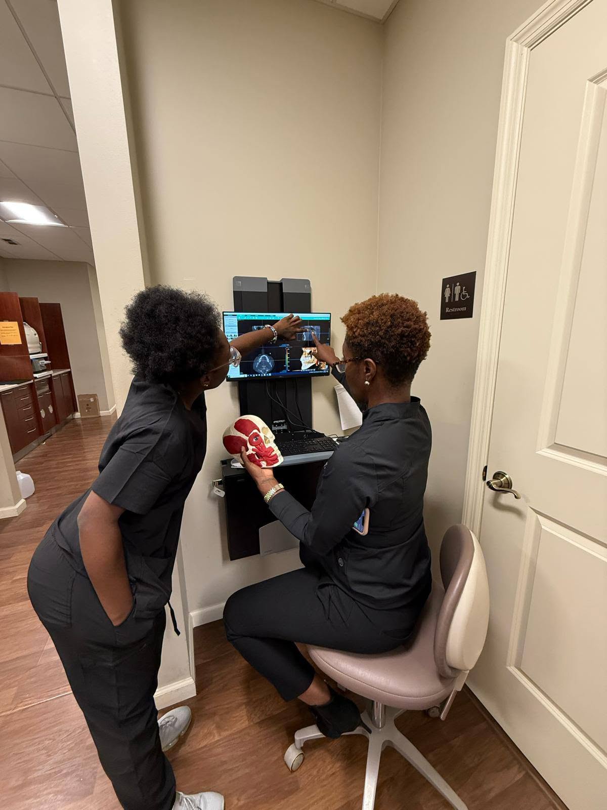 Our team points out details on a 3D dental scan on the monitor next to a skull model