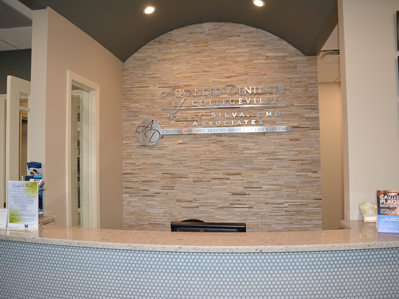 Front reception desk and stacked stone sign wall in our dental office