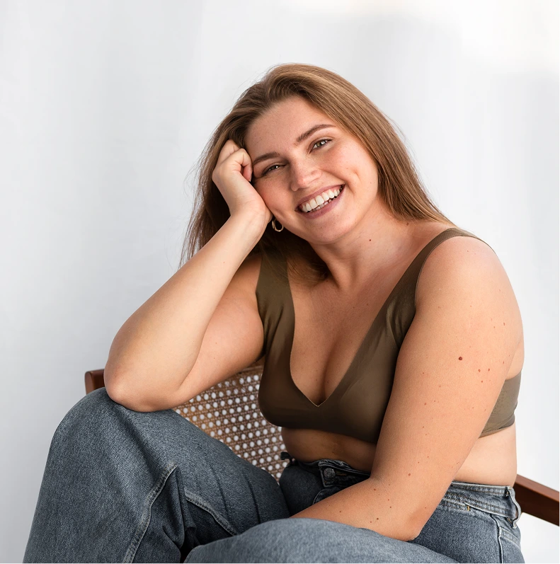 Smiling woman seated in jeans, representing the low BMI gastric sleeve