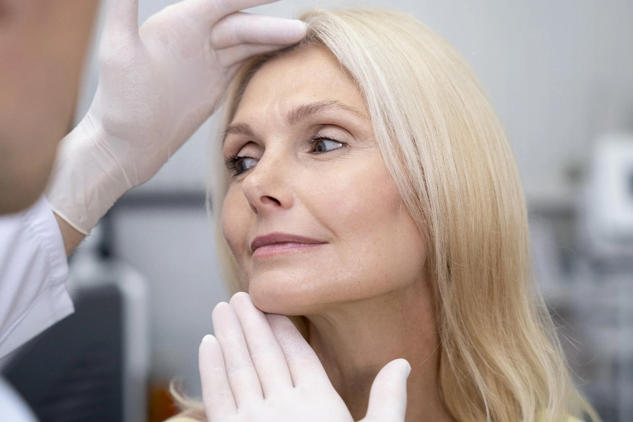 A surgeon examining a patient's forehead during a consultation