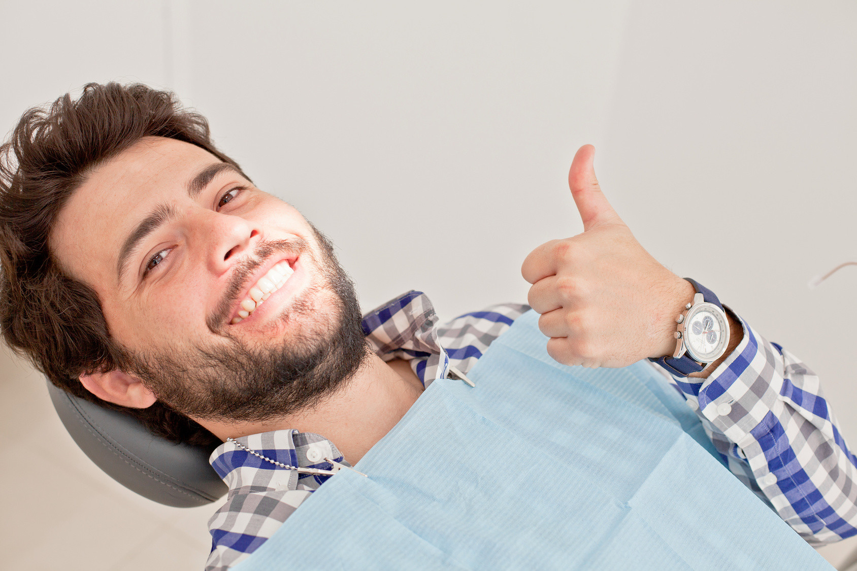 Smiling patient giving a thumbs up in the dental chair after tooth decay treatment