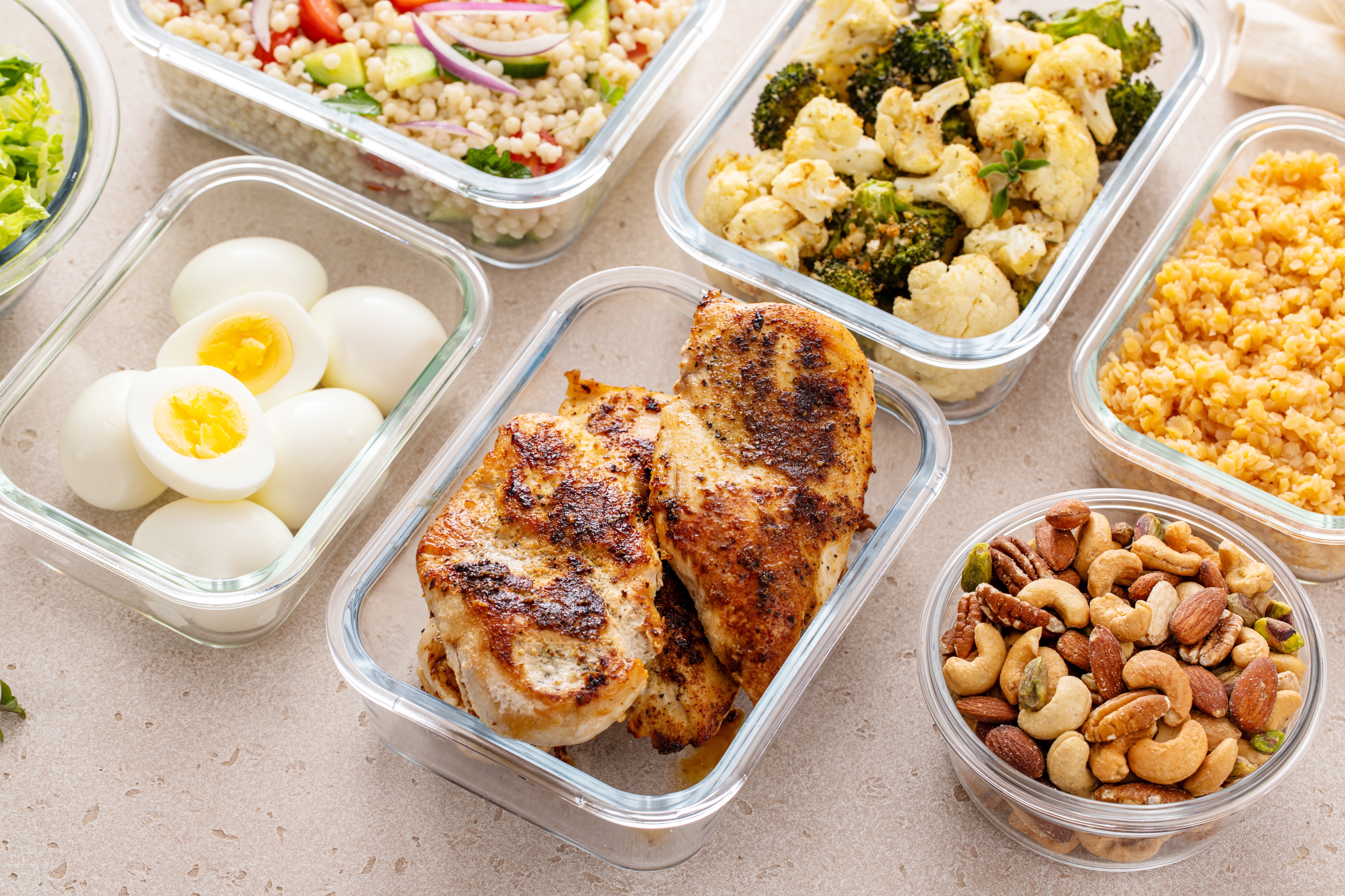 Glass meal-prep containers with grilled chicken, boiled eggs, vegetables and nuts, the kind of high-protein meals eaten after bypass