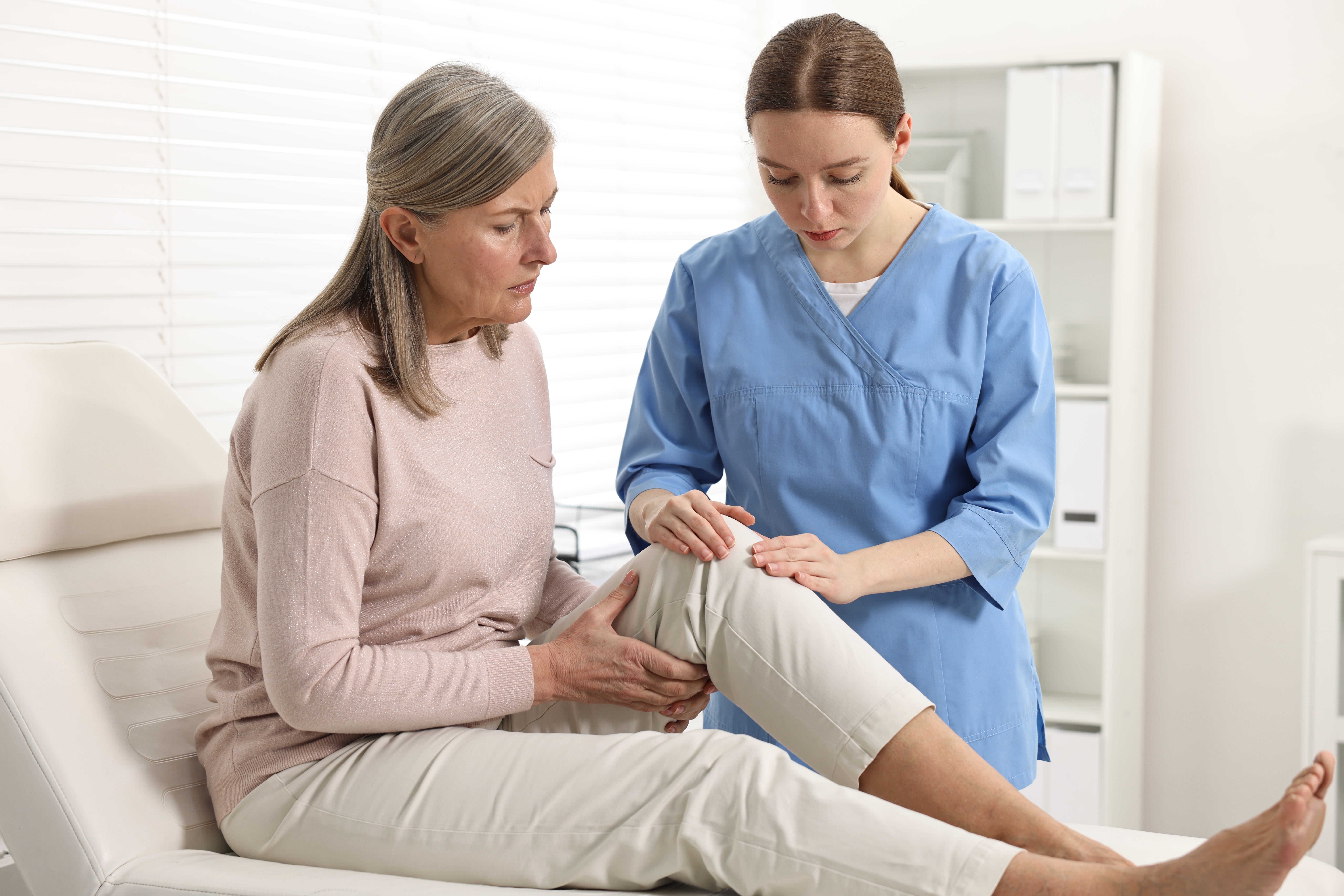 A nurse practitioner examines an older female patient's knee during a clinical consultation, illustrating a blog post compari