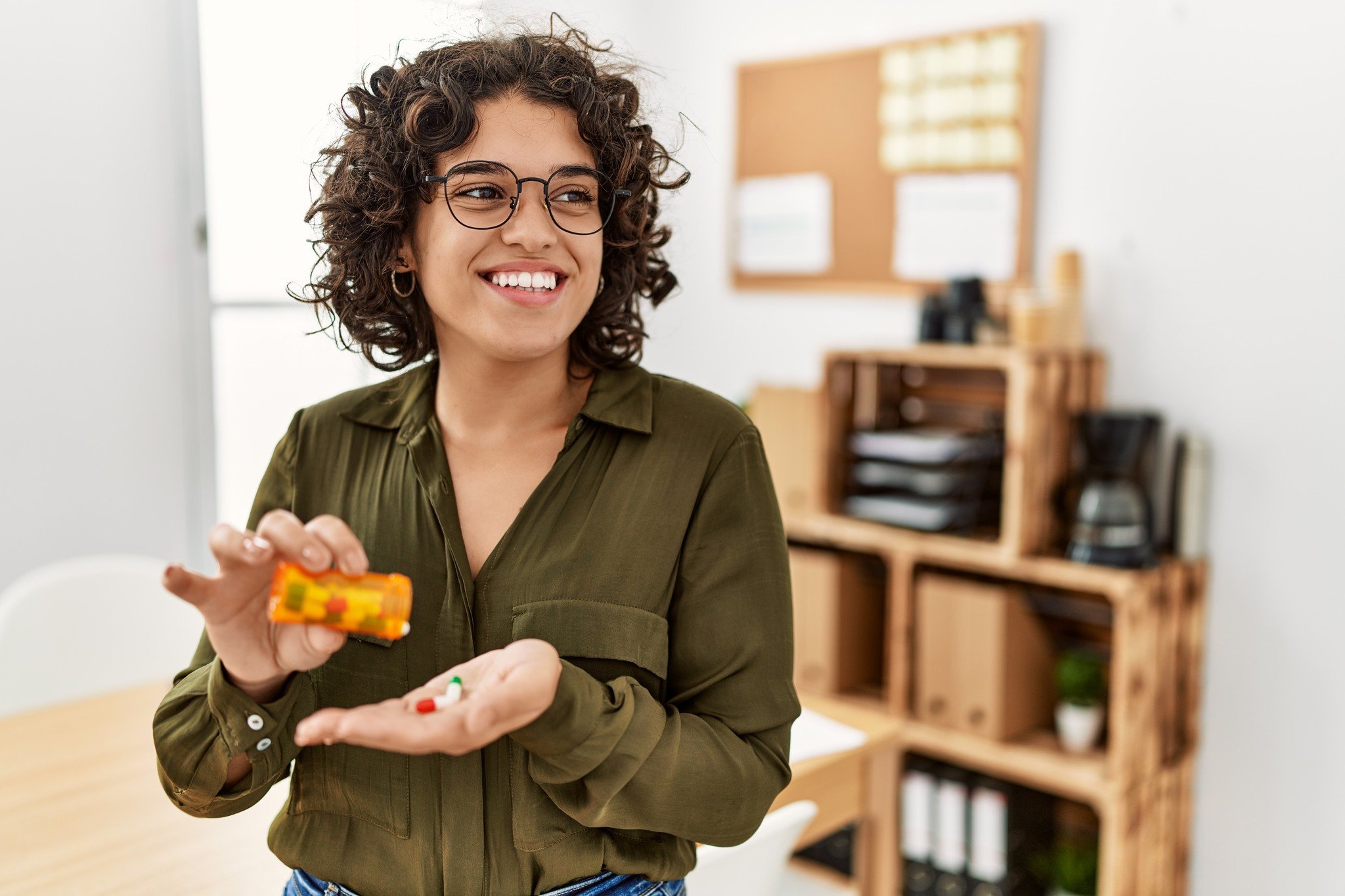 Smiling woman holding a pill bottle and medication in her hand, used to illustrate a post about medication management for dep