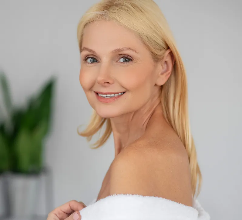 Smiling mature woman with blonde hair wrapped in a white towel