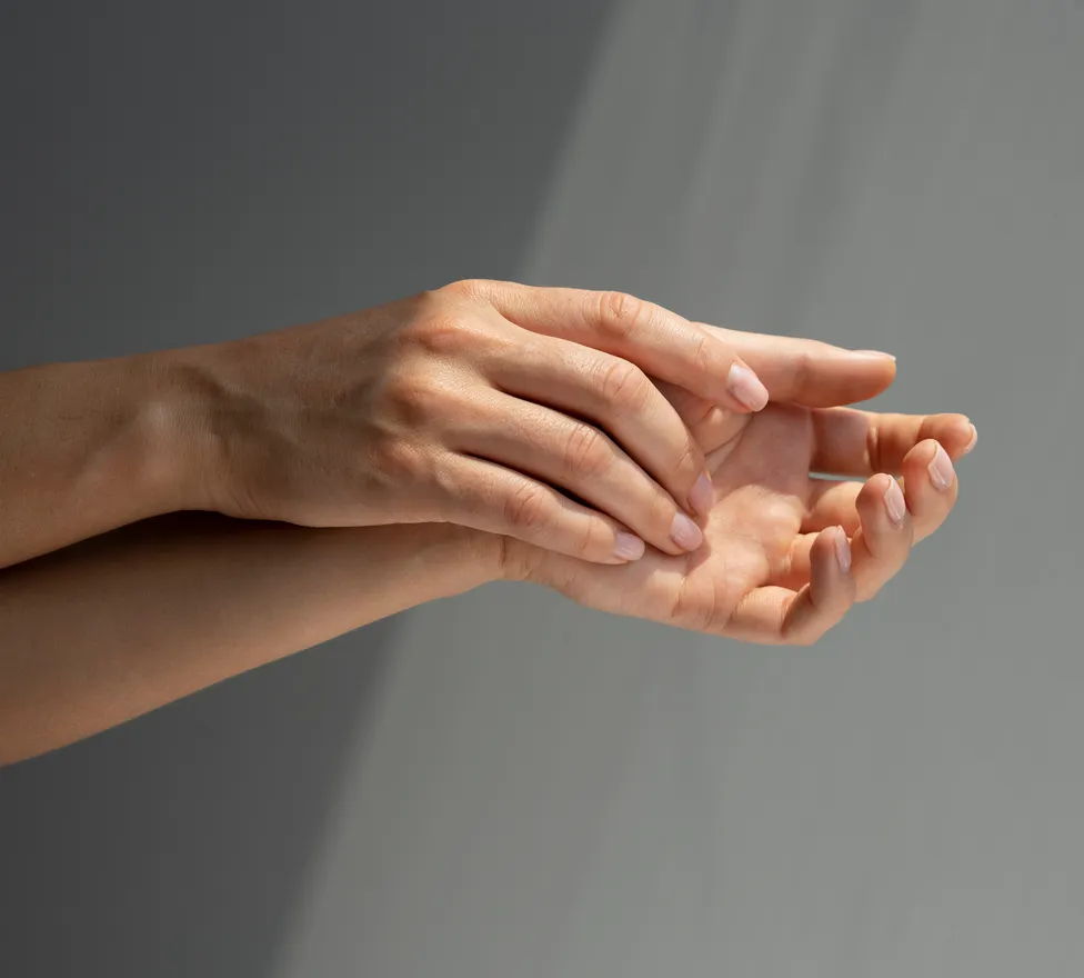 Two hands held palm up against a grey wall