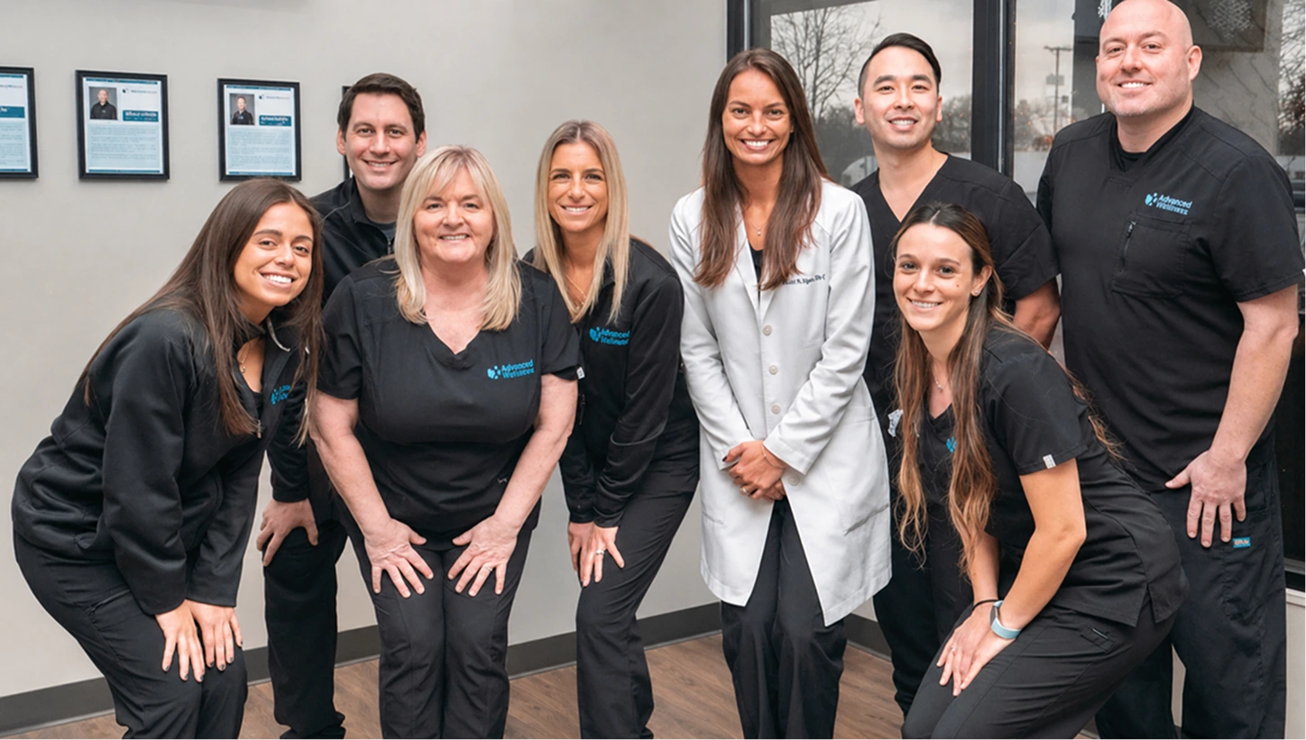 Advanced Wellness dental and medical team of eight staff members posing together in office