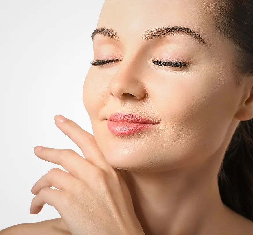 Woman with eyes closed touching her face, displaying smooth, glowing skin