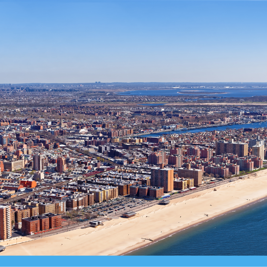 Aerial view of a densely populated urban coastline with sandy beach, residential buildings, and waterways