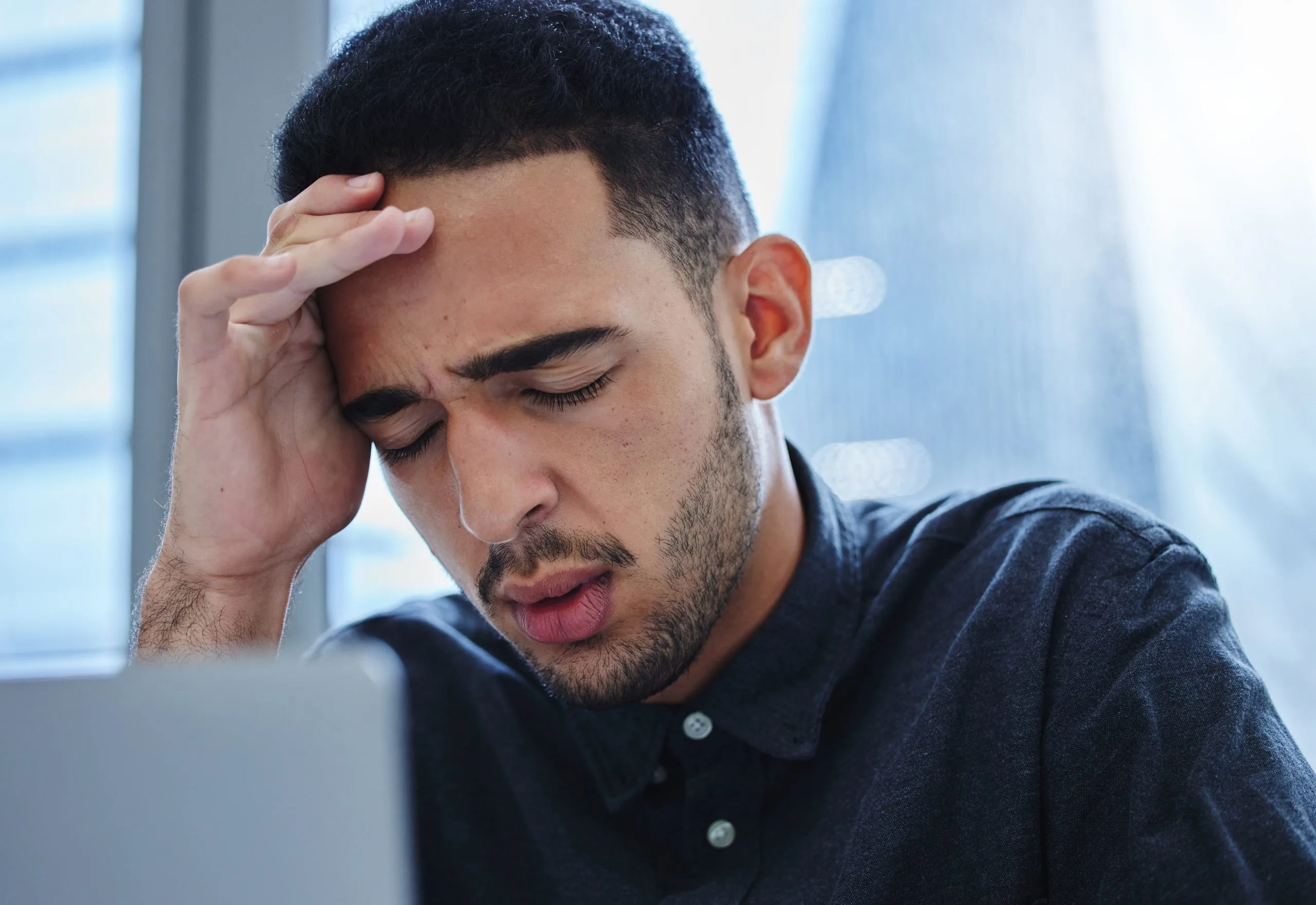 Stressed man holding his forehead in frustration.