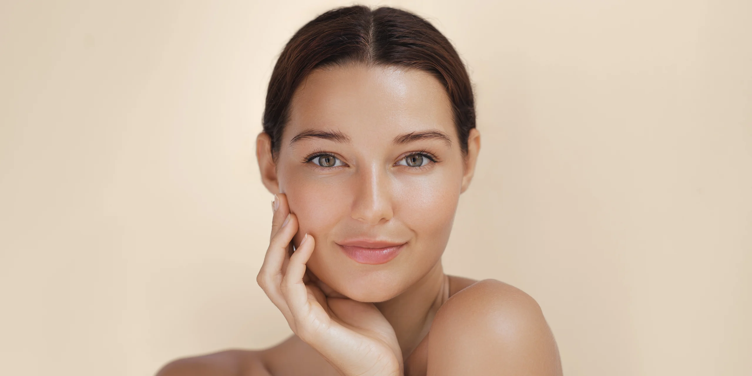 Close-up of a woman with smooth, glowing skin against a soft beige background