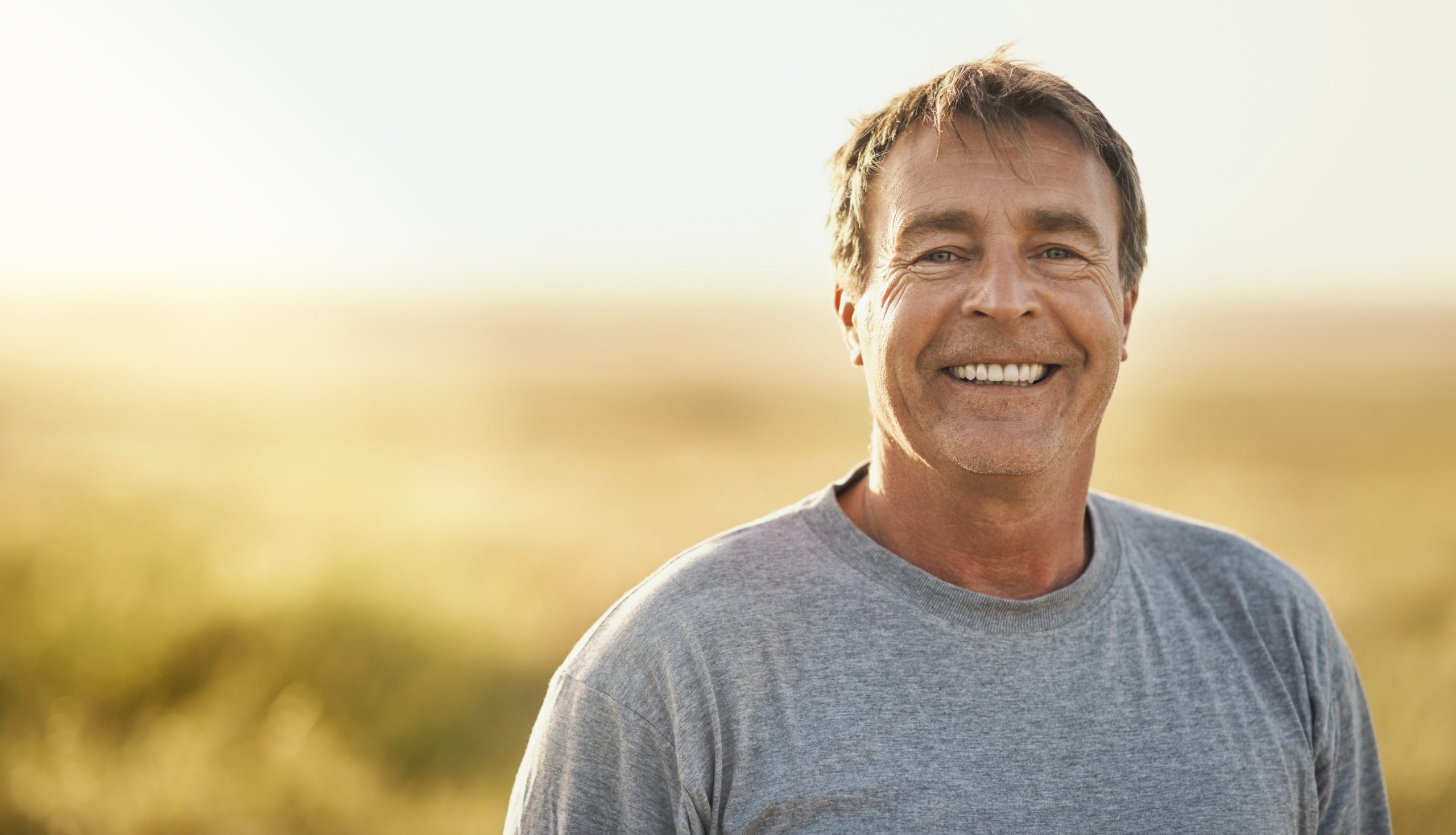 Senior man smiling outdoors in a summer field