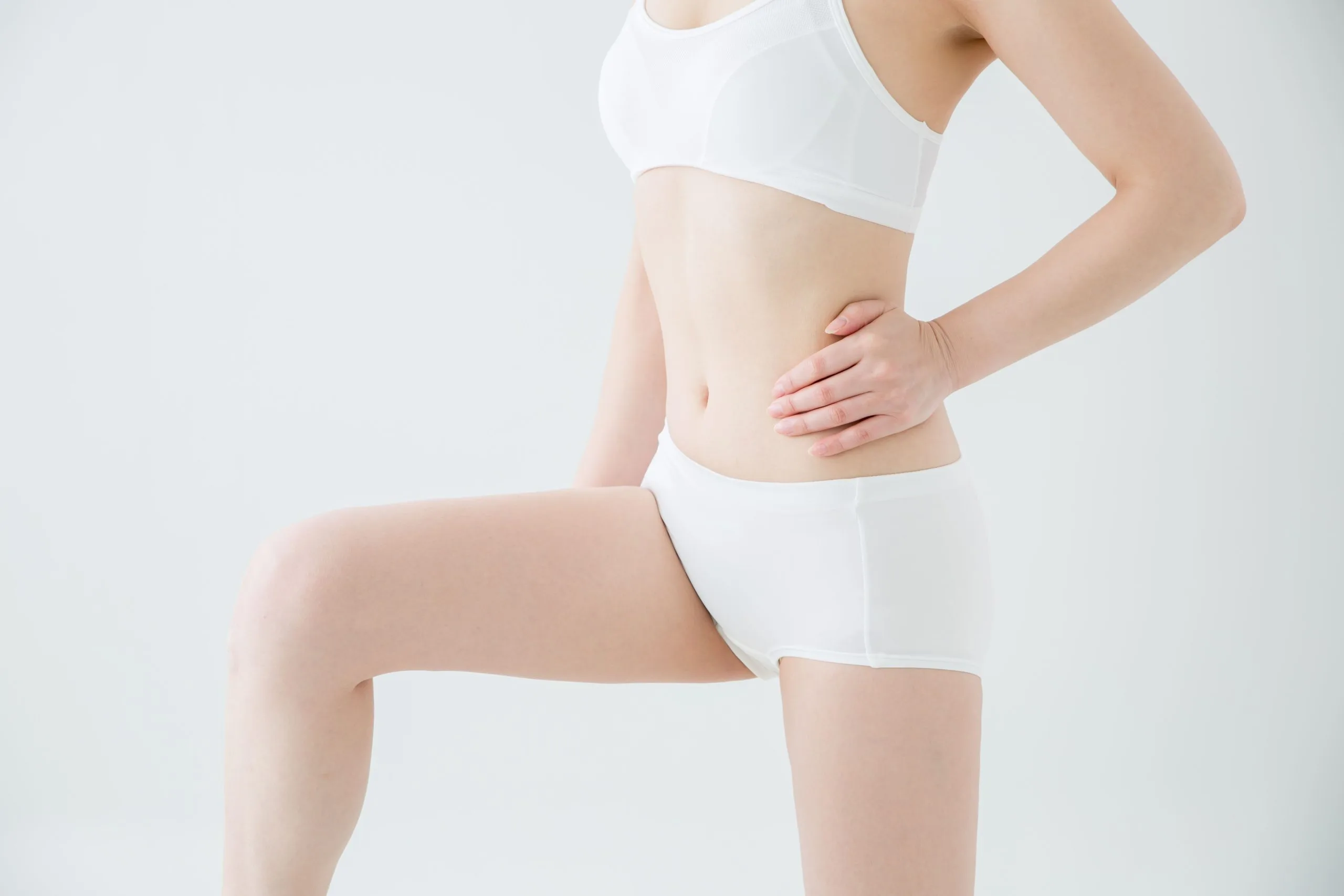 Woman in white undergarments touching her abdomen