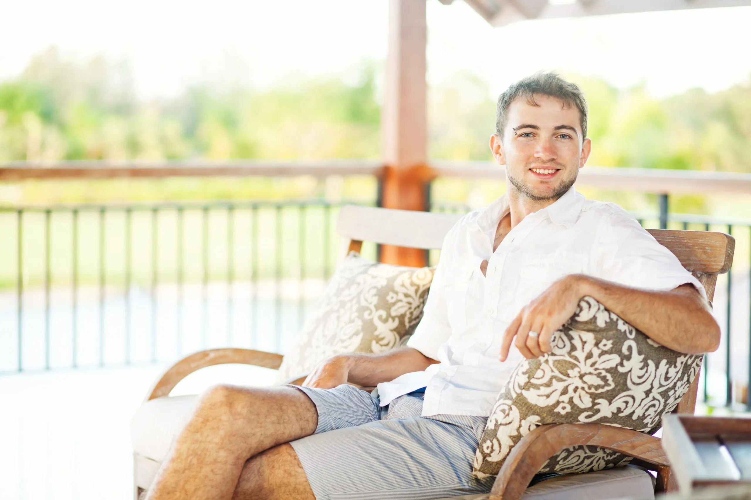 Man smiling while relaxing on a chair in a bright living room with outdoor views