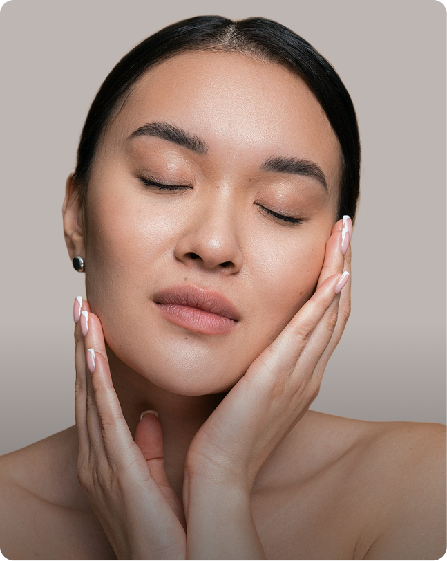 Woman with eyes closed touching her face demonstrating skin treatment results