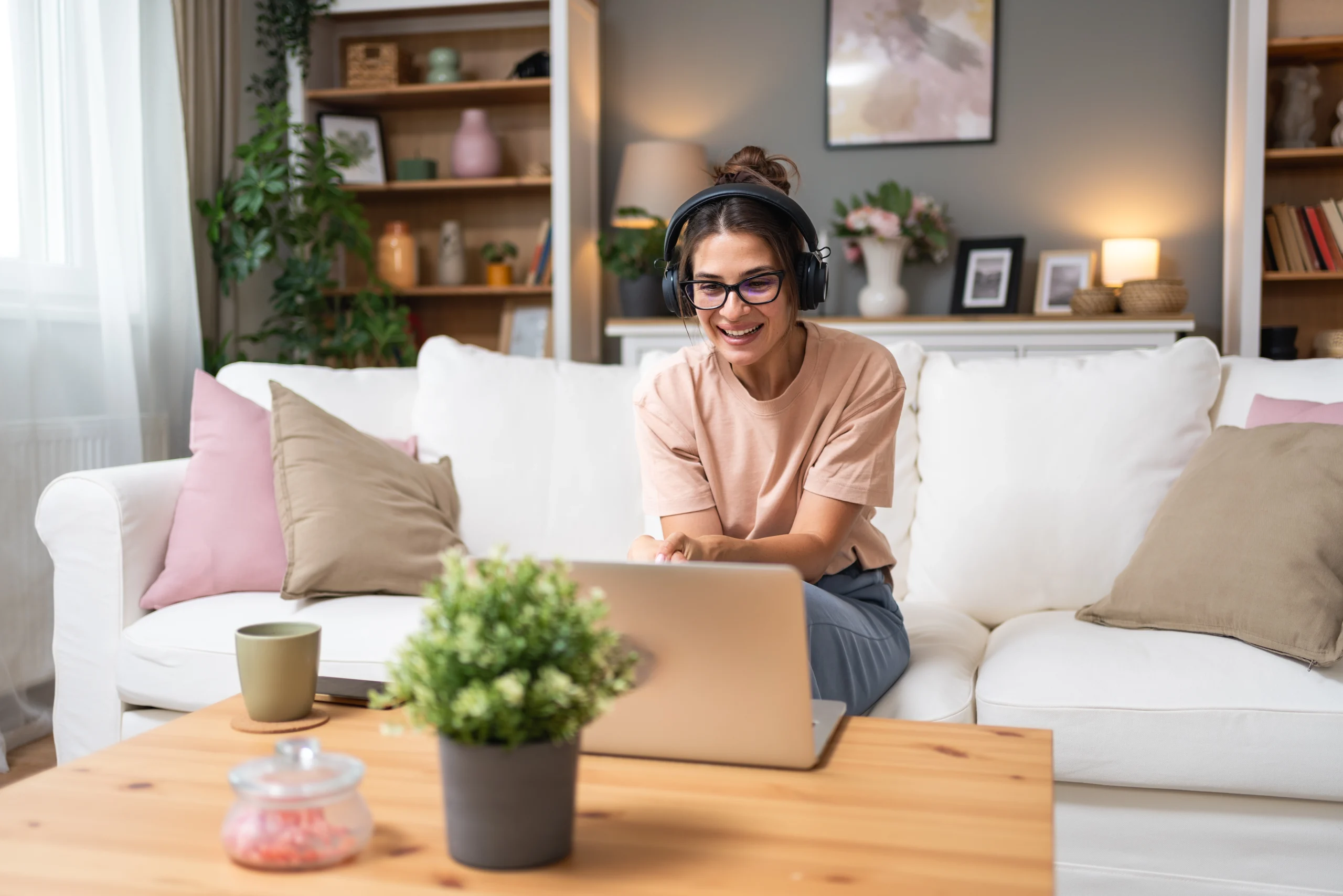 Woman wearing headphones and glasses on a laptop during a calm at-home video session