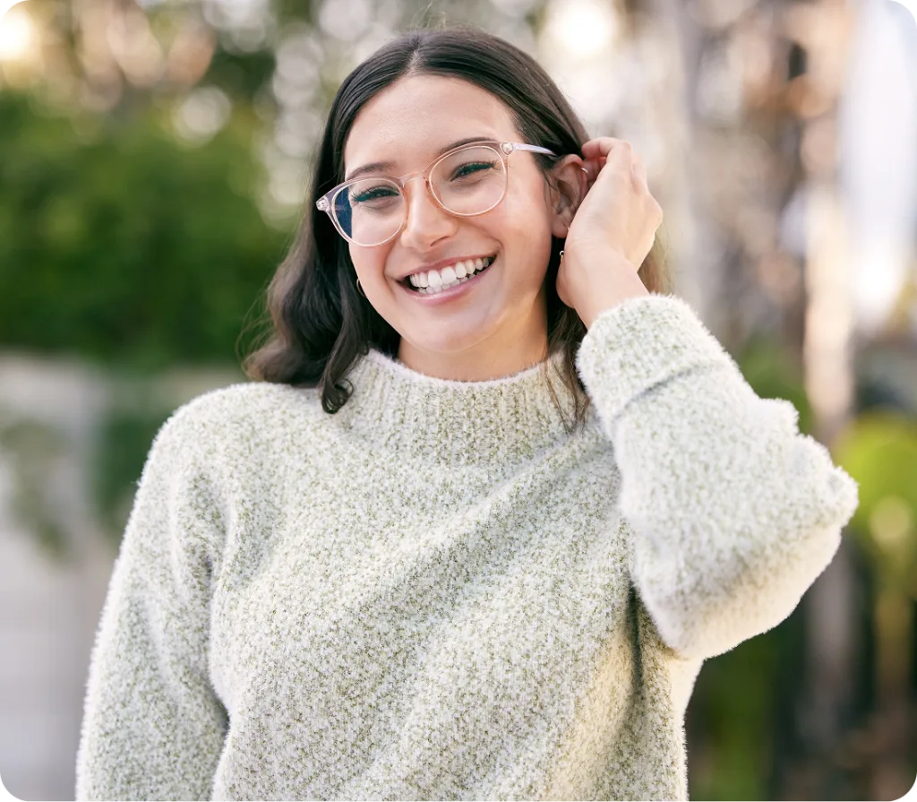 Smiling woman wearing glasses and cream sweater outdoors
