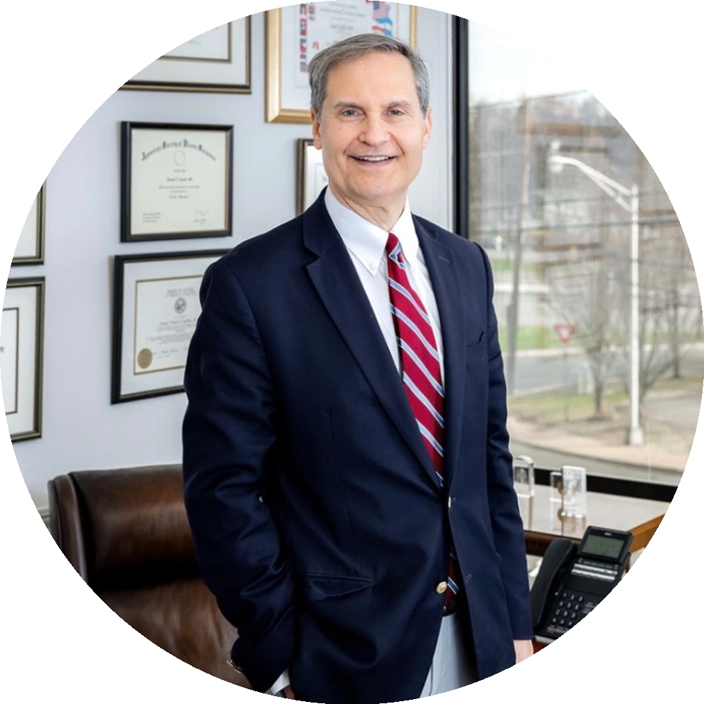 Joseph Capella, M.D. standing in his office with framed certifications and credentials on the wall behind him