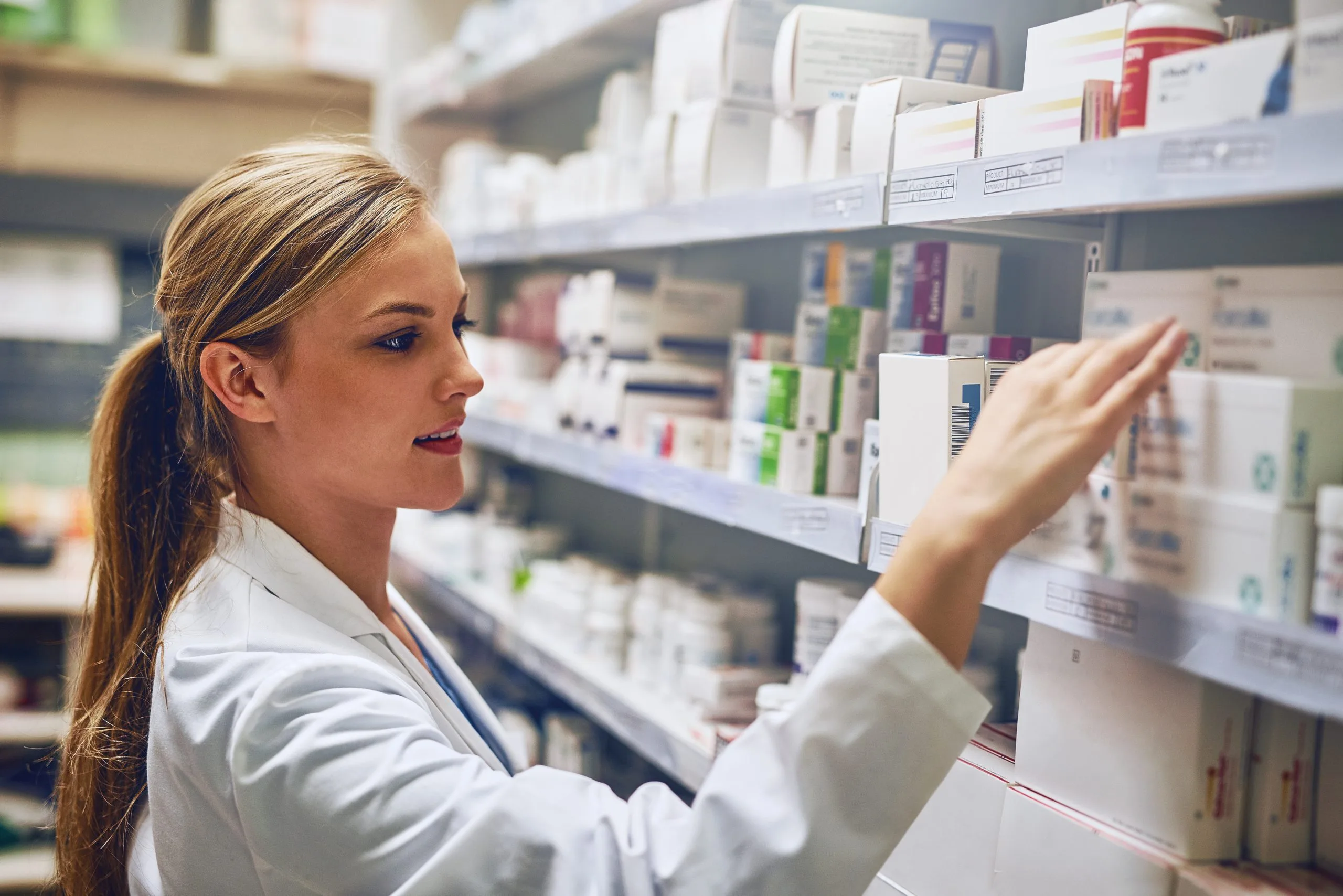 Pharmacist selecting medication from shelves in a compounding pharmacy