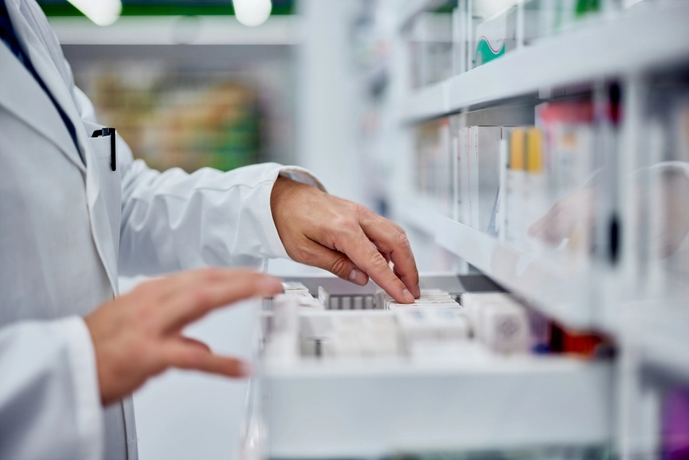 Pharmacist selecting medication from a drawer in a pharmacy storage area