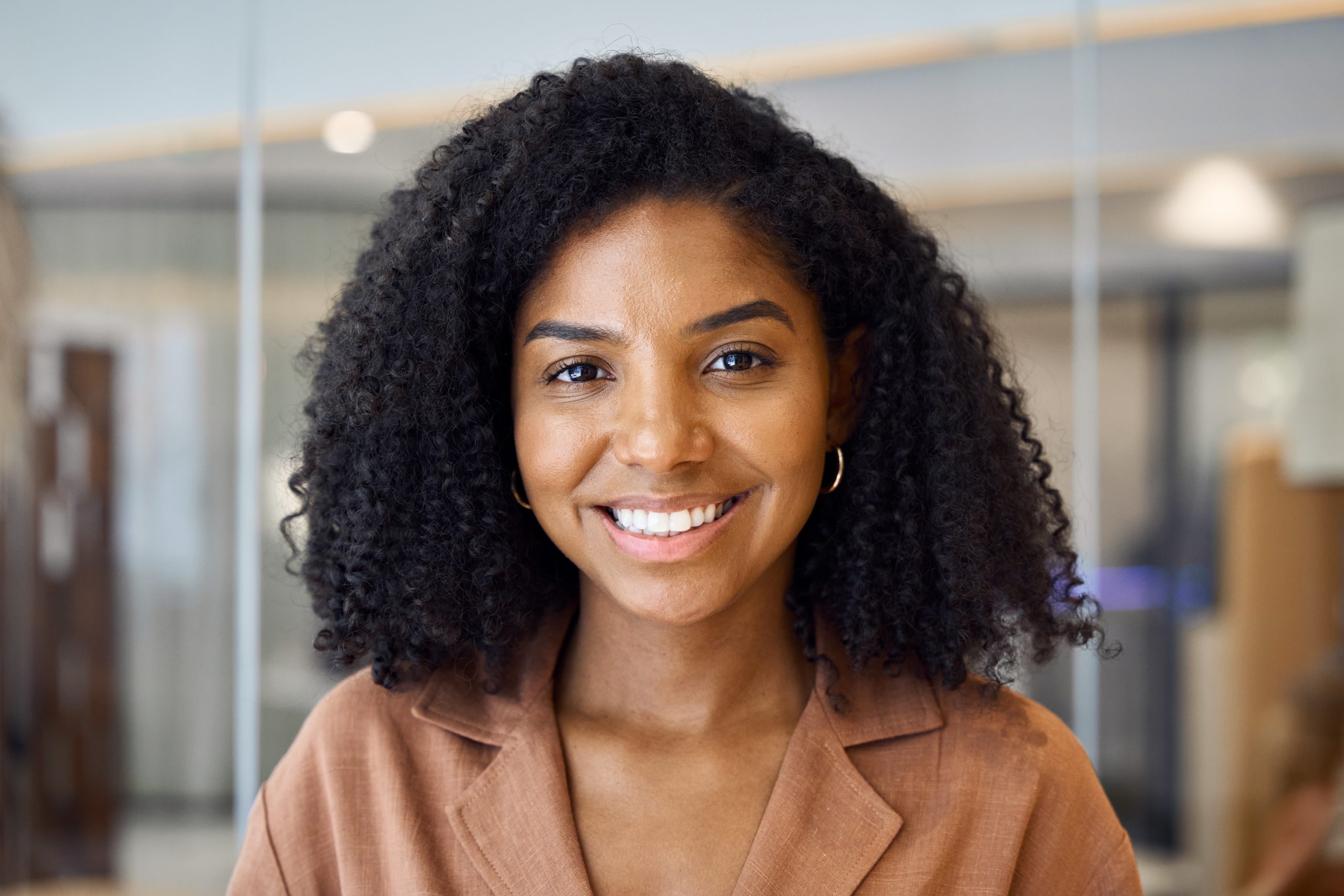 Smiling woman with curly hair standing in a bright room