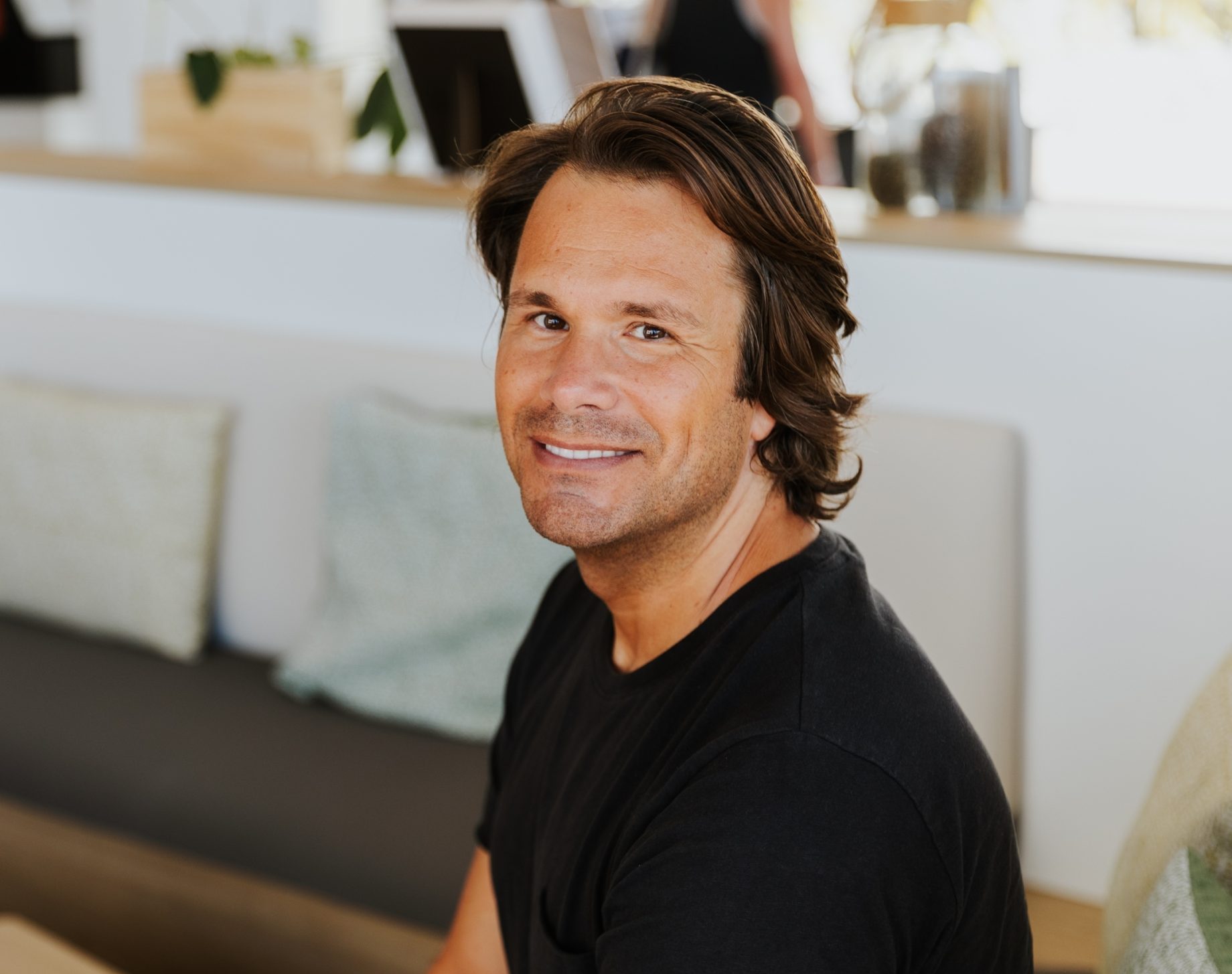 Smiling man in a black shirt sitting in a modern pharmacy waiting area
