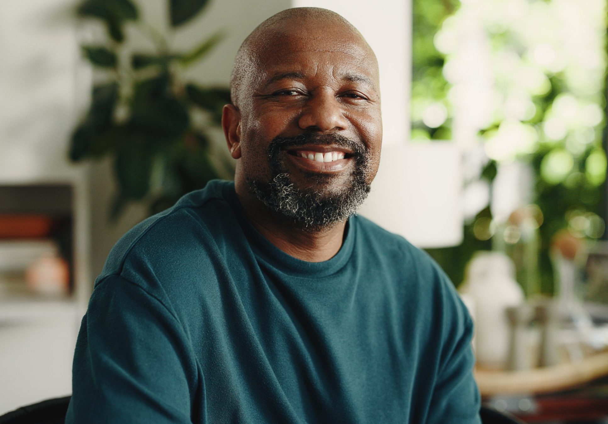 Smiling man relaxing at home surrounded by potted plants
