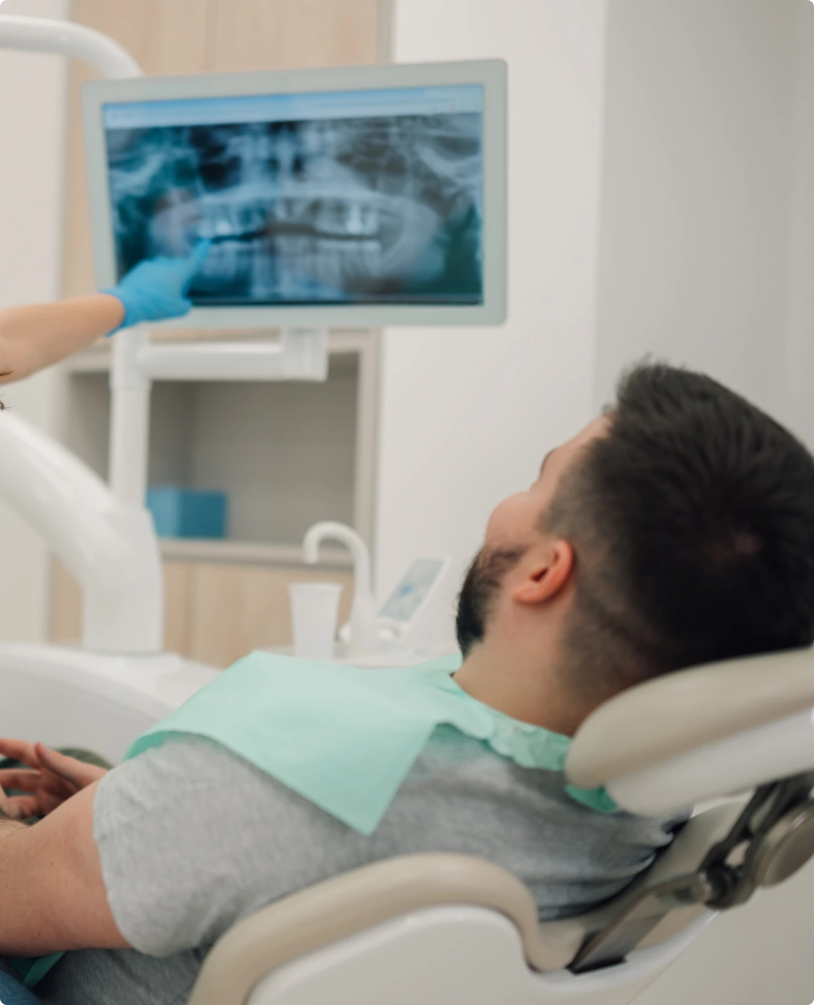 Clinician showing a patient dental X-ray on monitor during socket preservation consultation