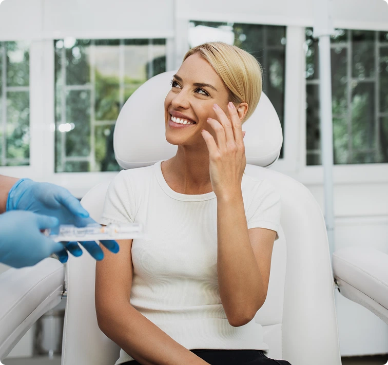 Clinician in blue gloves presenting PRP therapy vial to smiling patient in dental chair