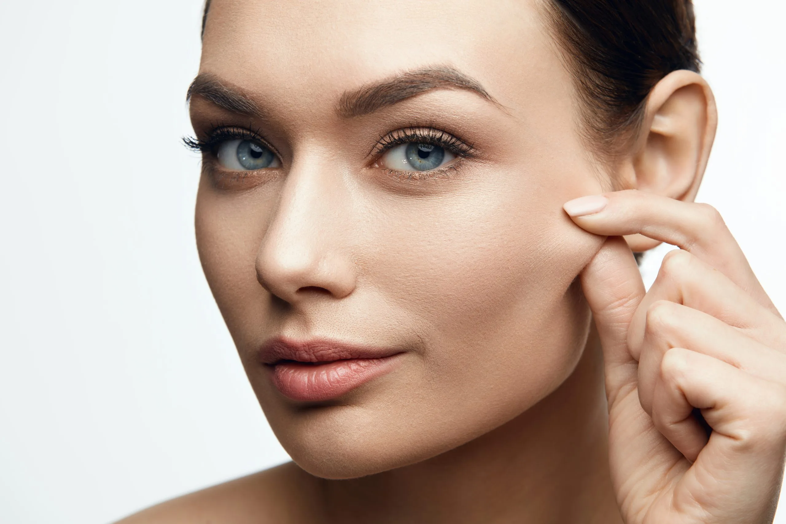 Woman with smooth facial skin touching her cheek and ear area