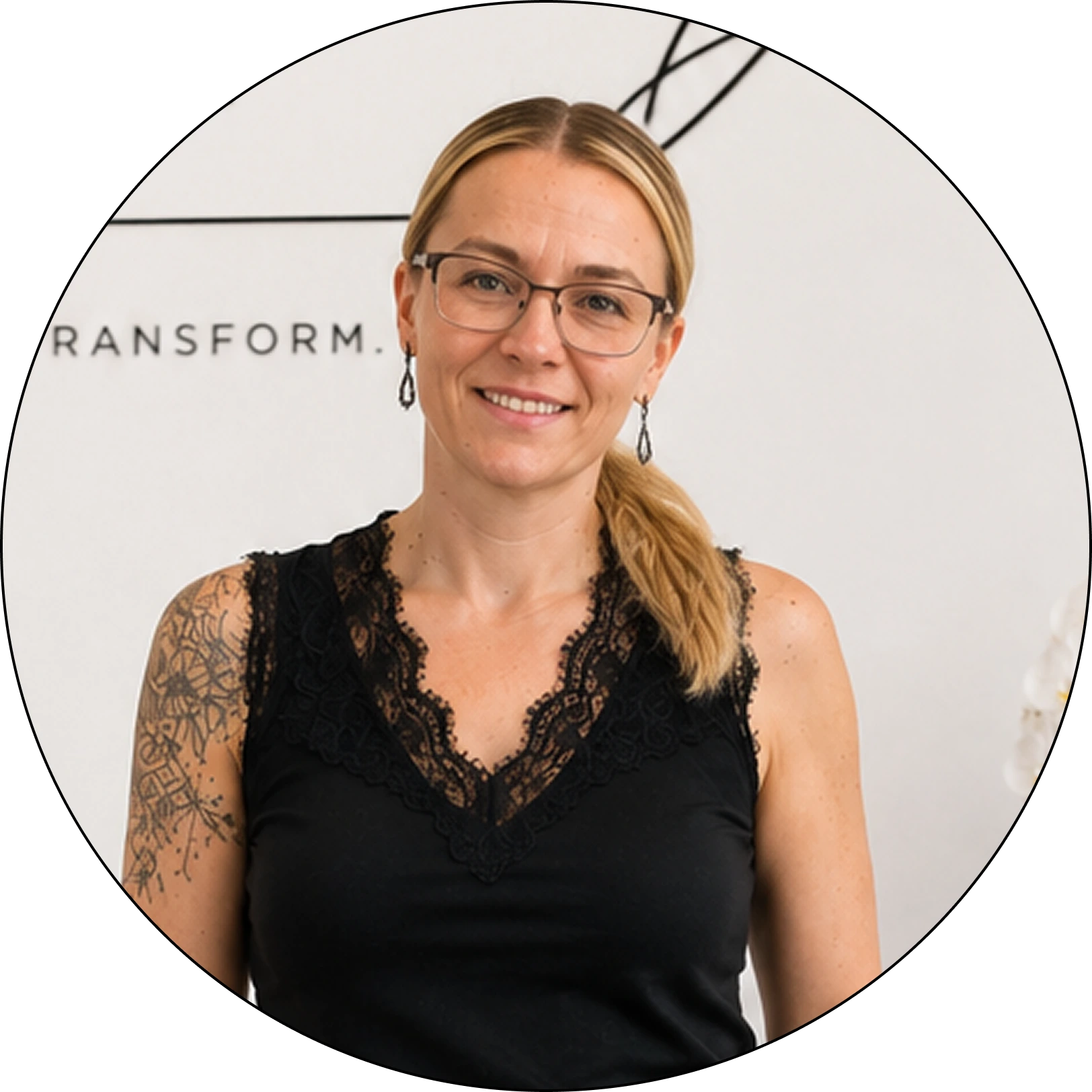 Team member smiling at camera wearing glasses and black lace top