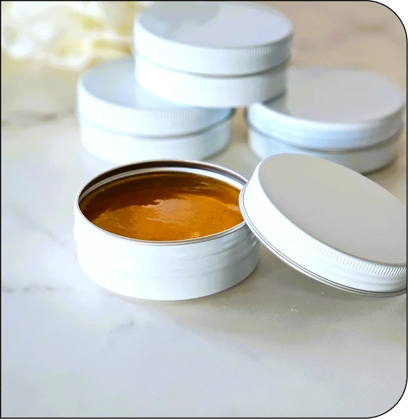 CNT Glow Bar skincare product jars with white lids, one open revealing golden-amber formula