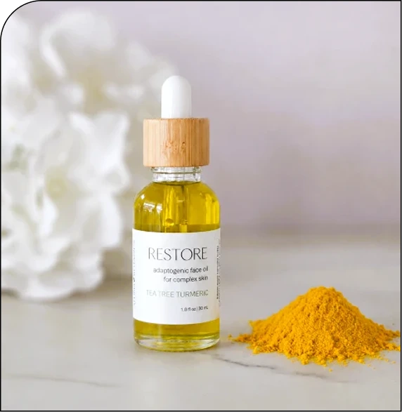CNT Restore antioxidant face oil bottle with dropper next to turmeric powder and white flowers