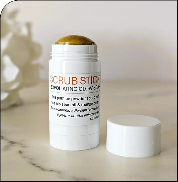 Scrub Stick Exfoliating Glow Soap with gold dome top and white cylindrical container, lid removed and placed beside it