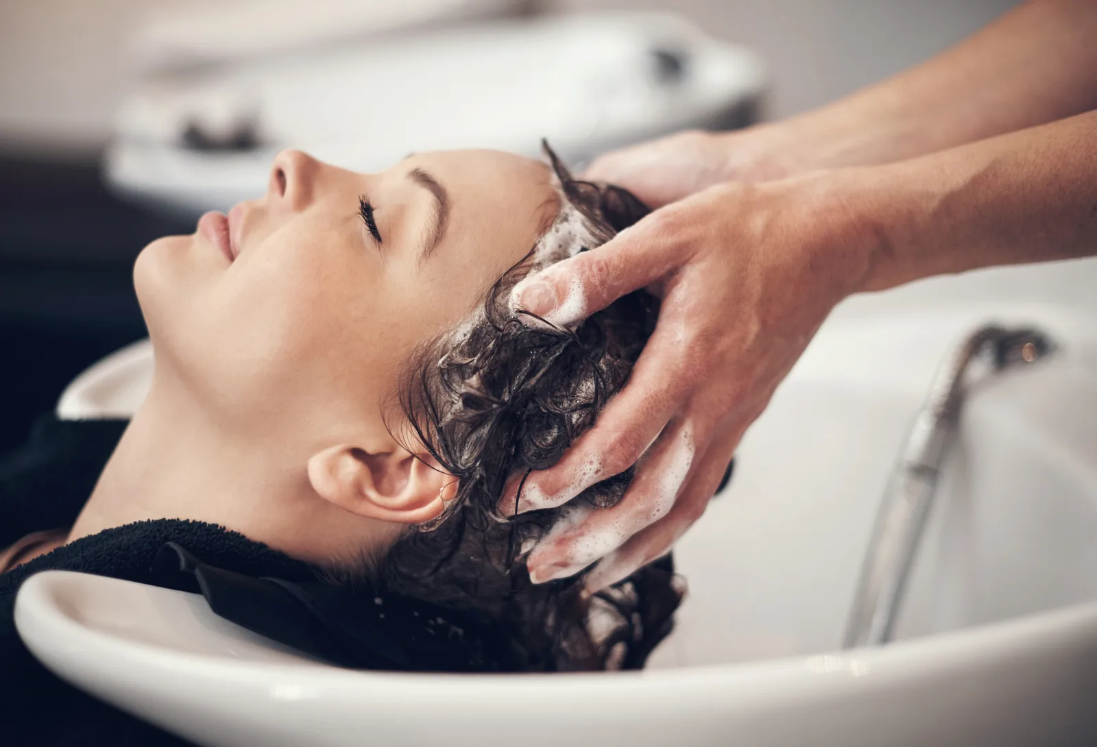 Client relaxing at a salon sink during a scalp shampoo and massage
