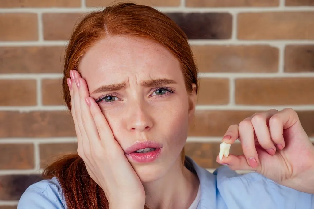 Woman holding a knocked-out tooth, a common dental emergency