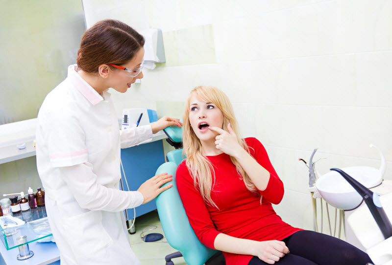 Dentist in white coat explaining oral health to patient seated in dental chair