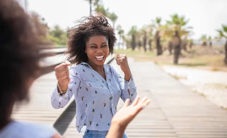 Woman smiling and gesturing enthusiastically during an outdoor conversation with another person