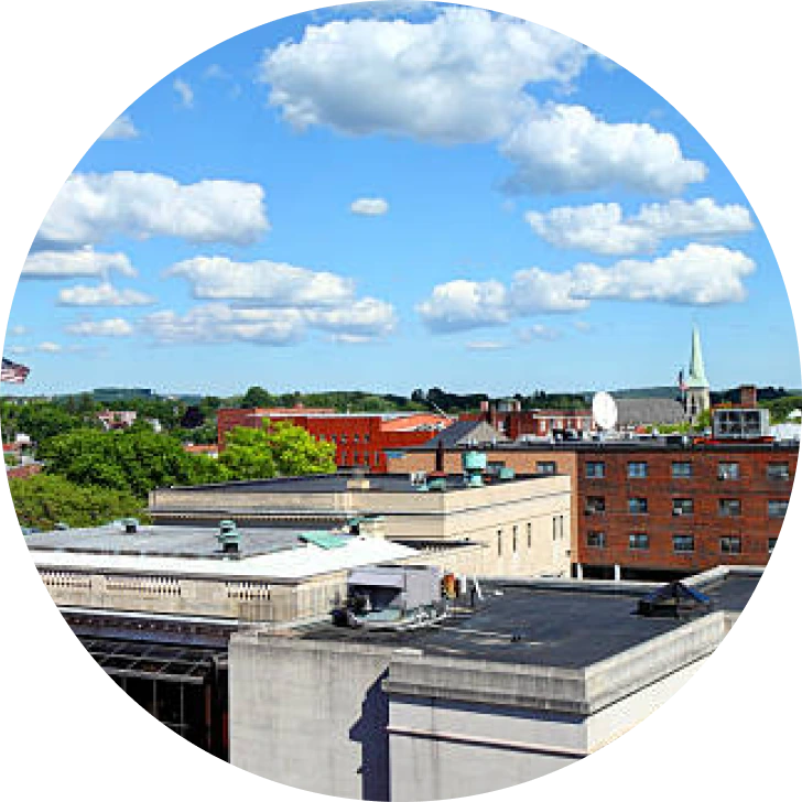 Aerial view of brick buildings and tree-lined streets under blue sky with white clouds