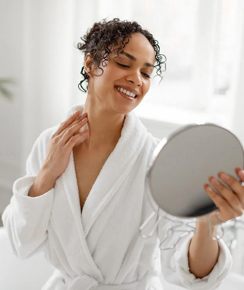 woman looking at her neck in the mirror