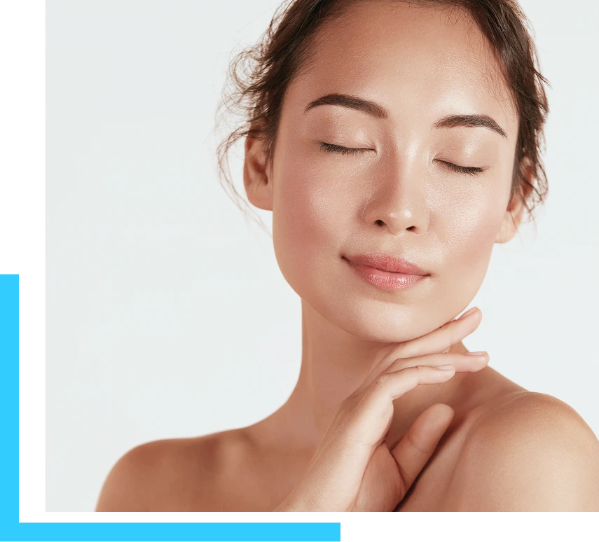 Woman with glowing, tightened skin touching her chin and neck against a neutral background