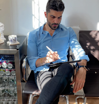 Dentist in blue shirt reviewing dental records on tablet in treatment room