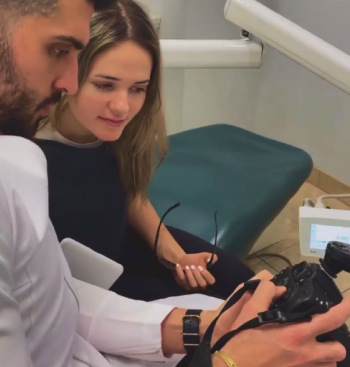 Man and woman smiling while looking at intraoral camera display during dental consultation