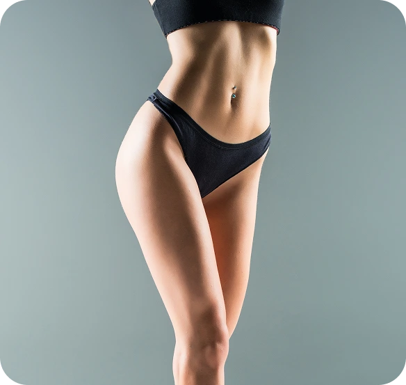 Person with defined abdominal muscles wearing black bikini bottom, standing against blue-gray background