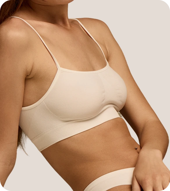Person in cream-colored sports bra shown from side profile in neutral pose