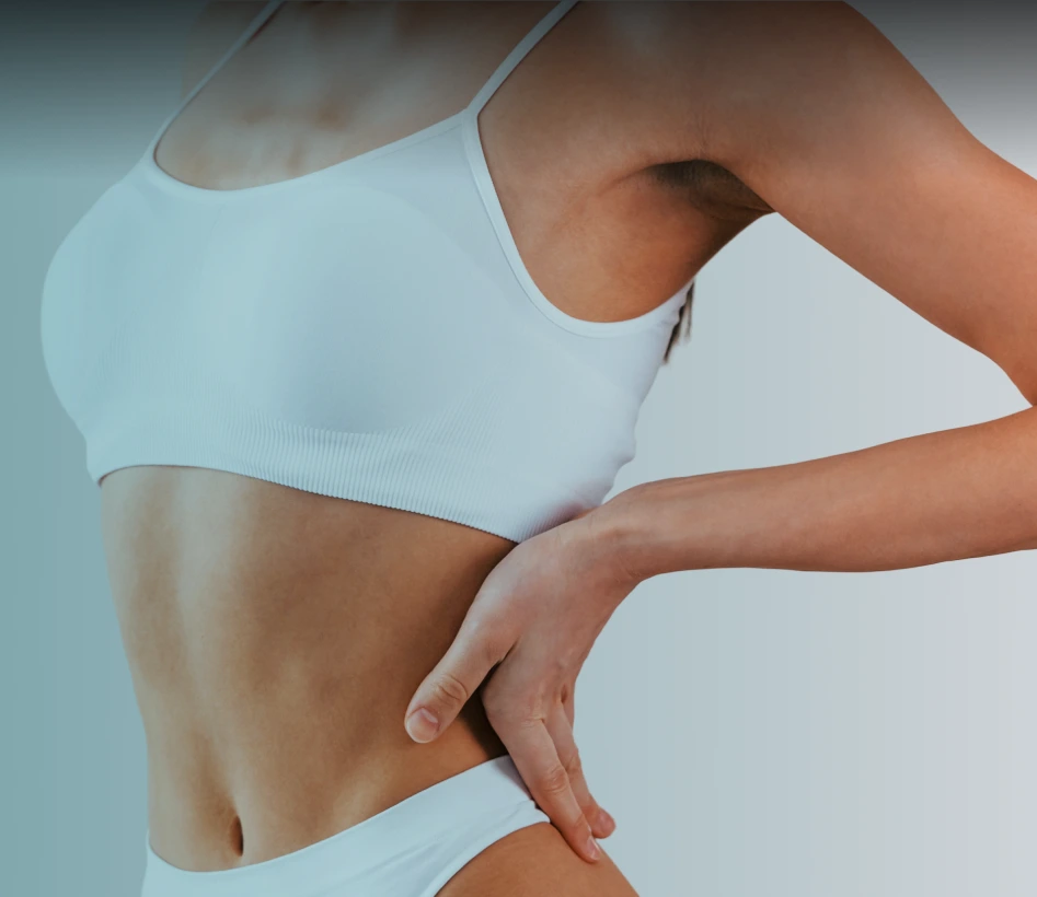 Woman in white crop top pinching abdominal area to demonstrate skin laxity
