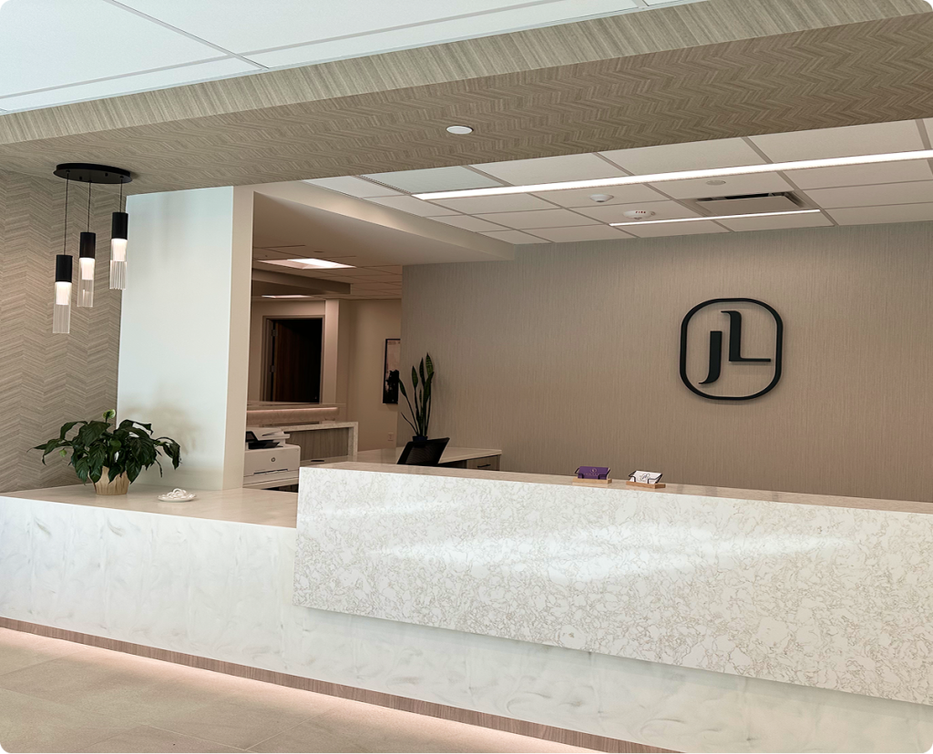 Modern reception desk at Jude LaBarbera MD Plastic Surgery with marble countertop and JL logo on wall