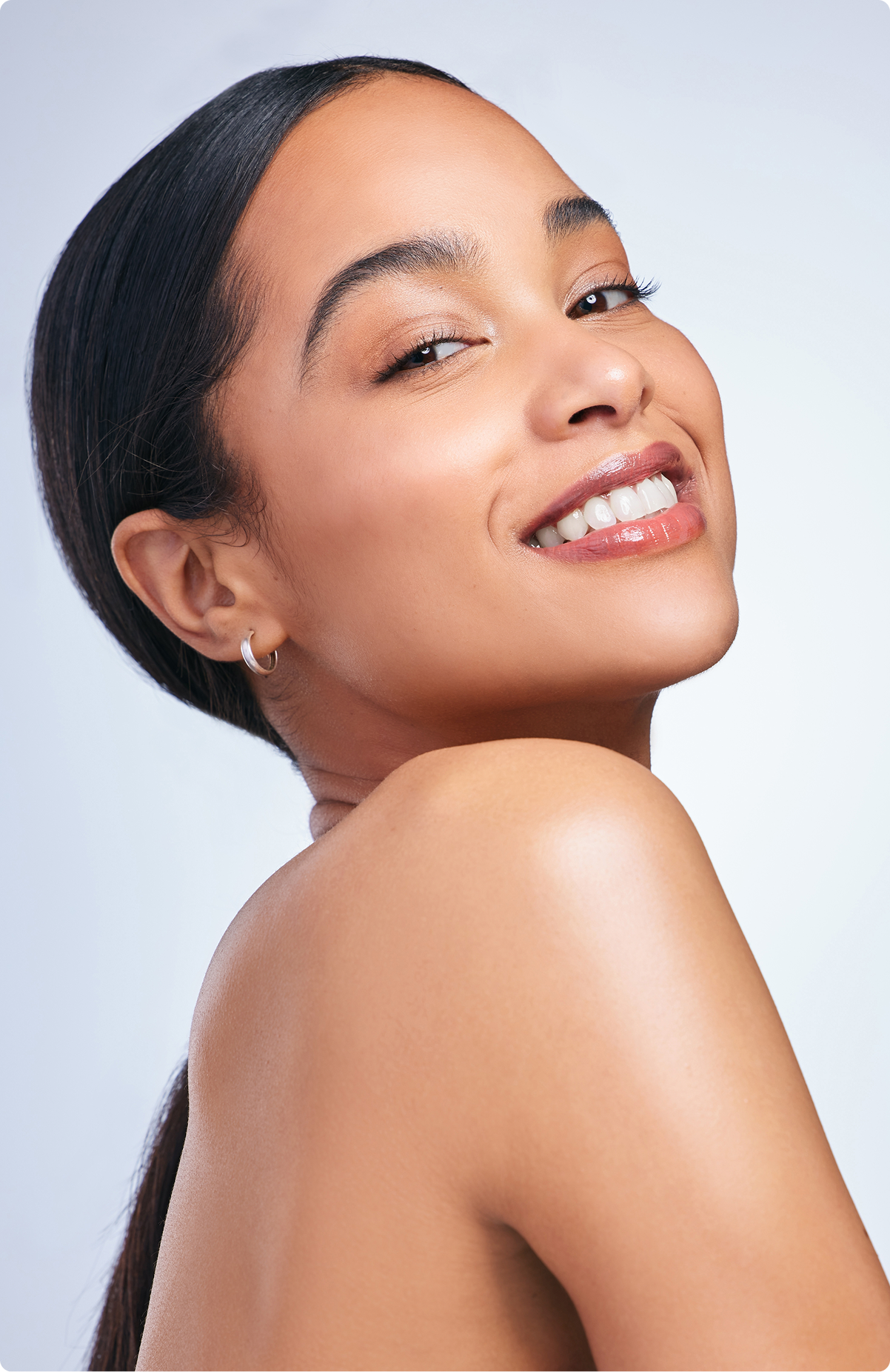 Woman smiling in profile against light blue background, showing facial contours