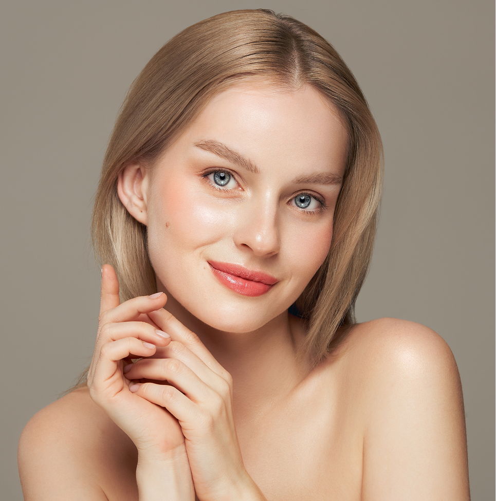 Woman with glowing skin touching her face, demonstrating facial rejuvenation results