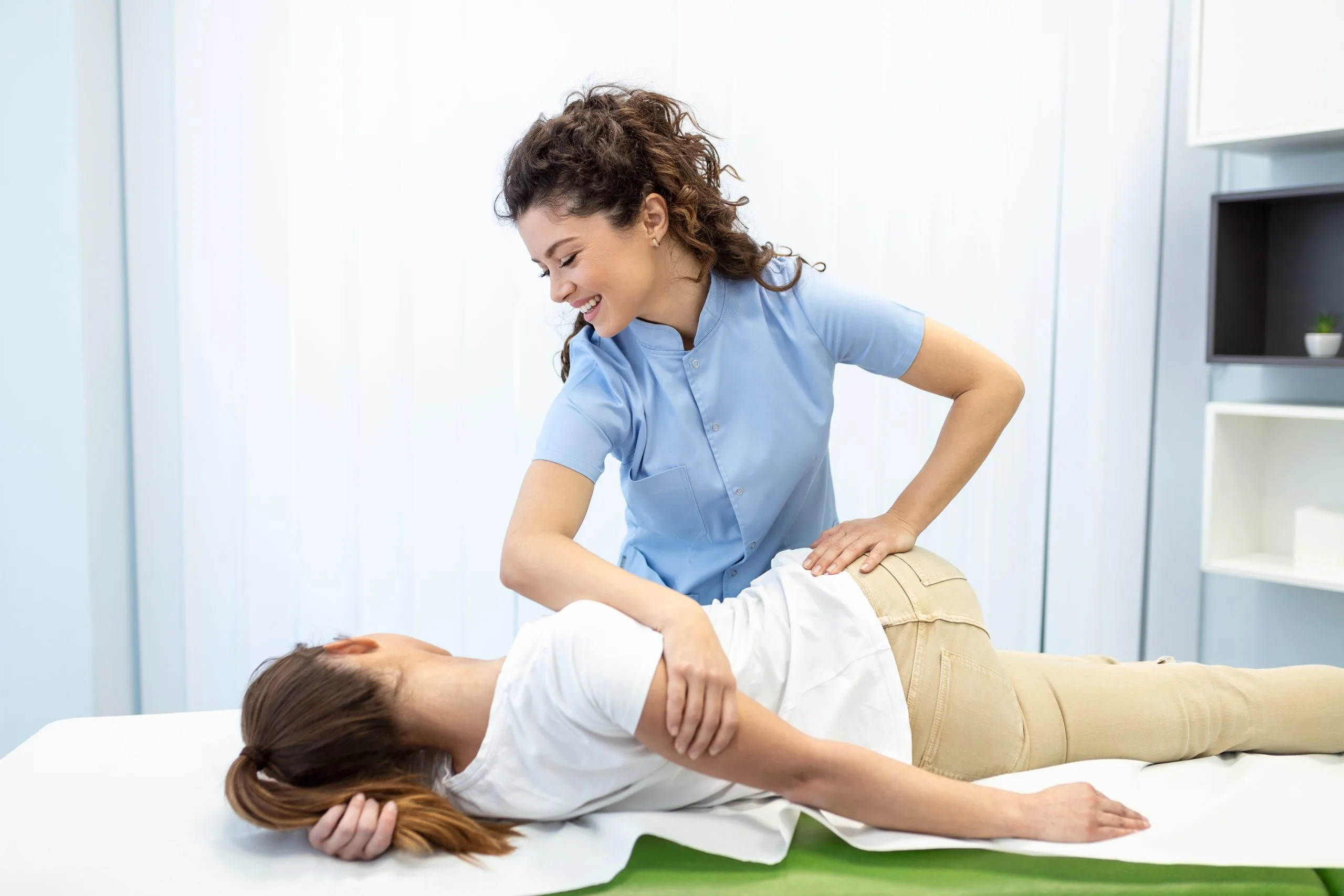 Chiropractor performing a back adjustment on a patient lying face down on a treatment table